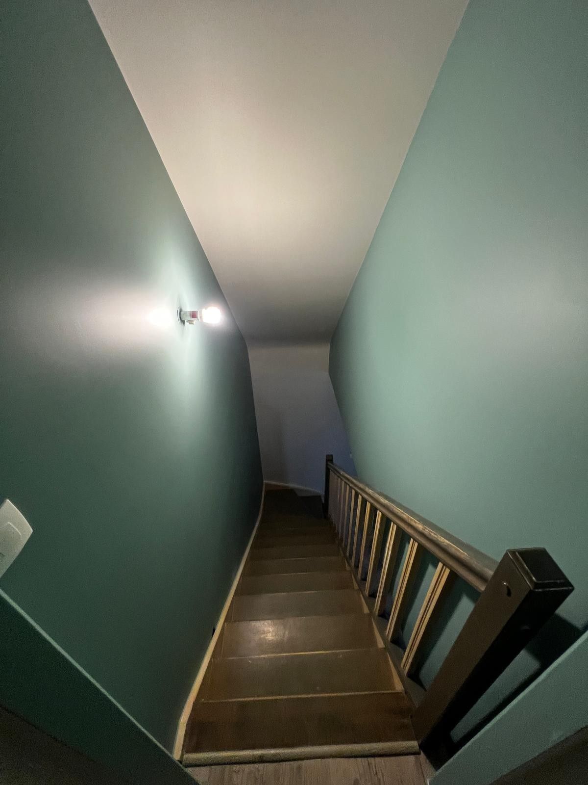 Cage d’escalier repeinte en vert, avec escalier en bois