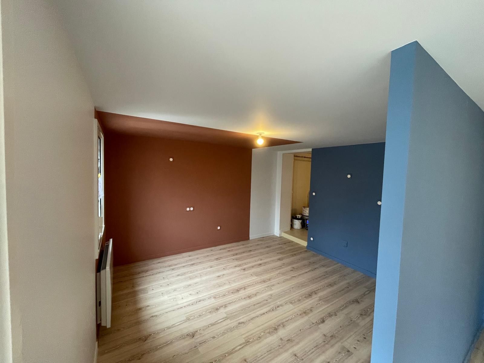 Pièce repeinte avec un mur terracotta et un mur bleu, sol stratifié