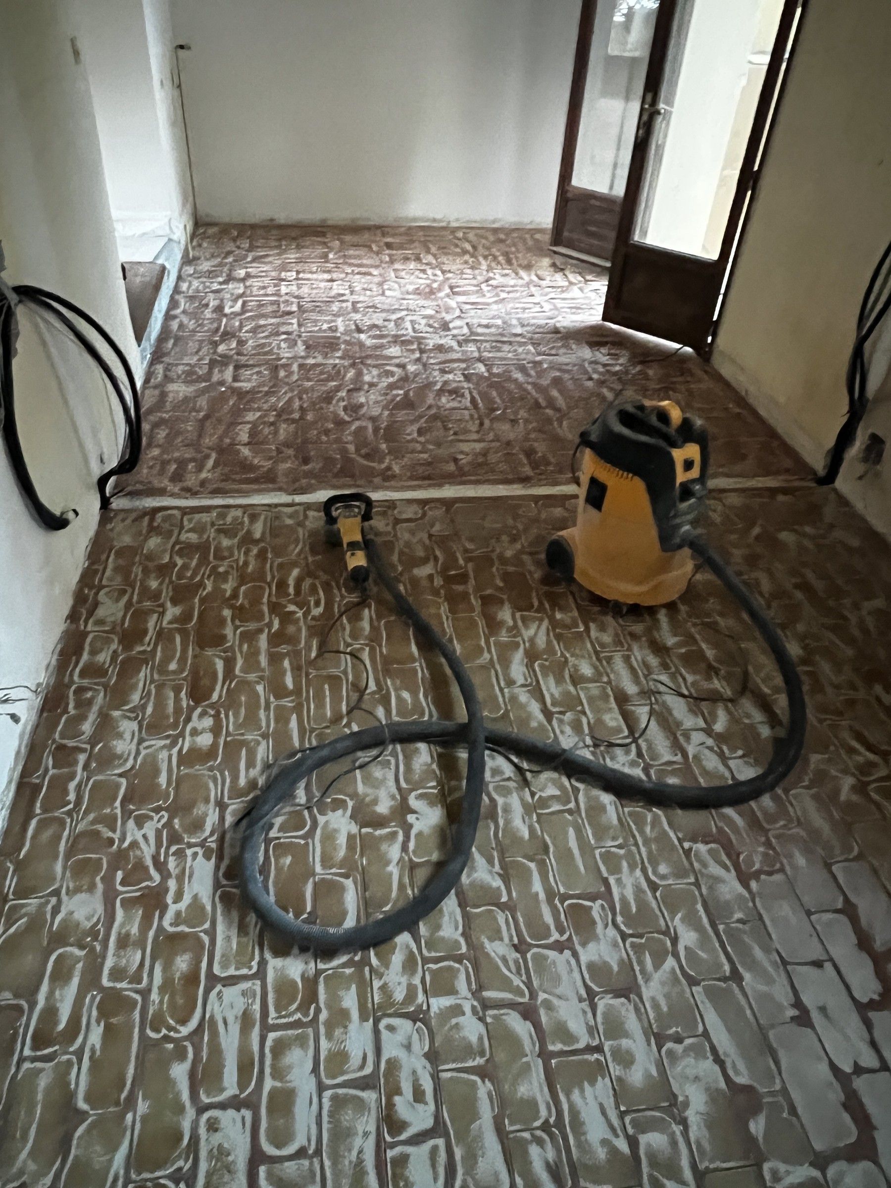 Ancien sol à motif brique en cours de préparation, avec aspirateur de chantier