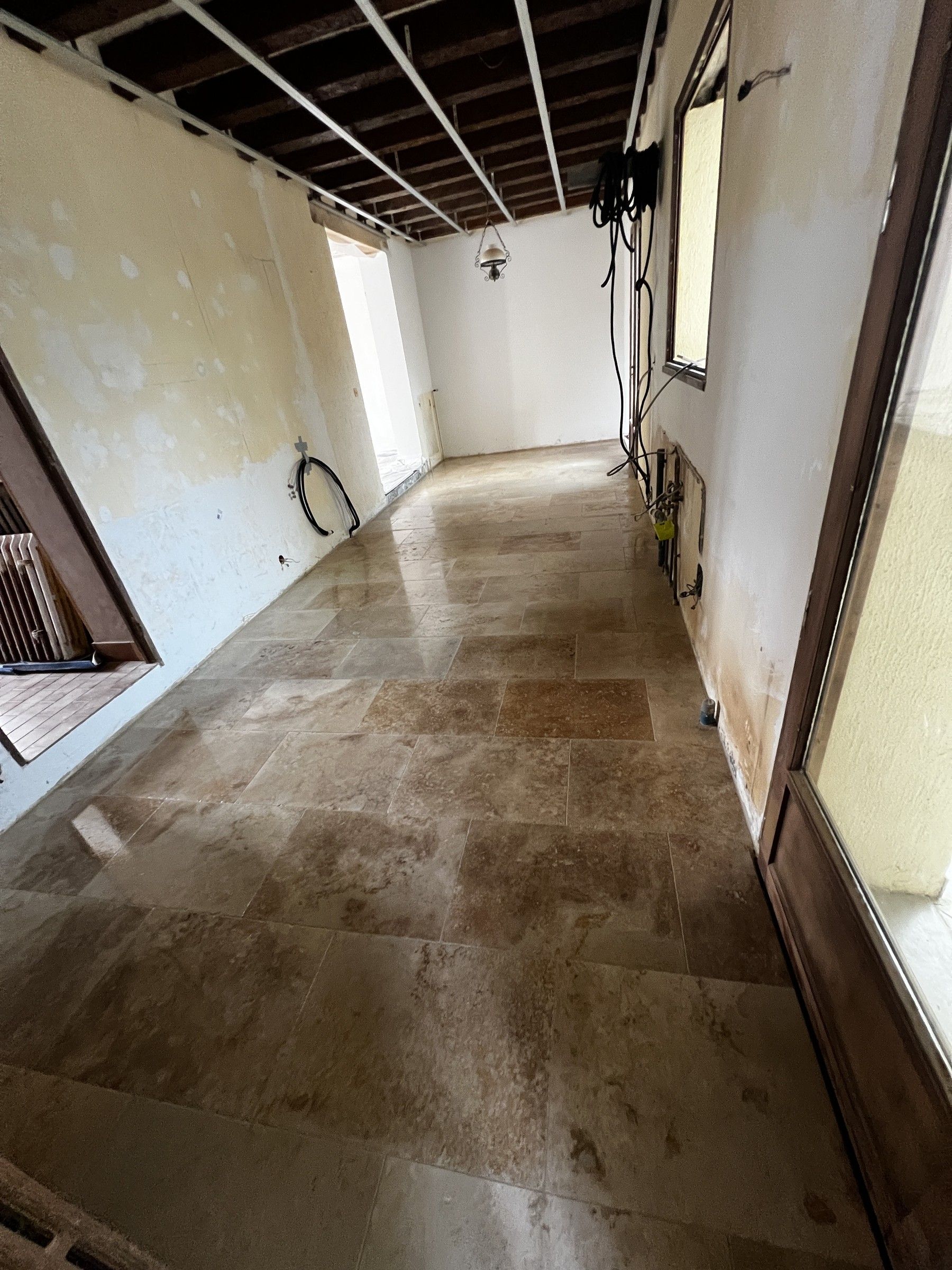 Pièce en rénovation avec un sol en dalles aspect pierre posé et des murs décapés