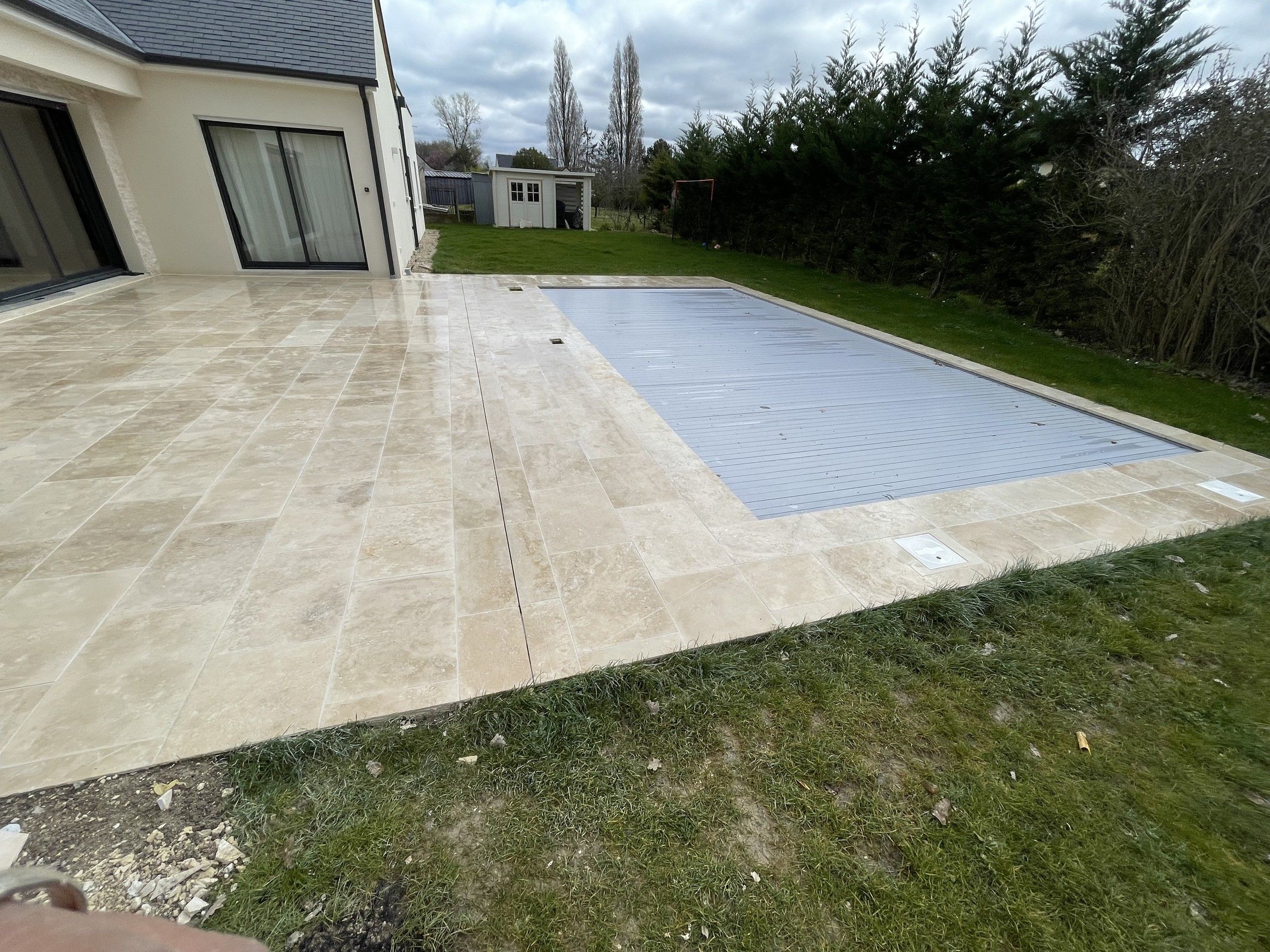 Terrasse en dalles de travertin posée autour d’une piscine